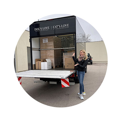 Katharina Miklauz in piedi davanti al nostro camion aperto che consegna prodotti a un rifugio per animali 